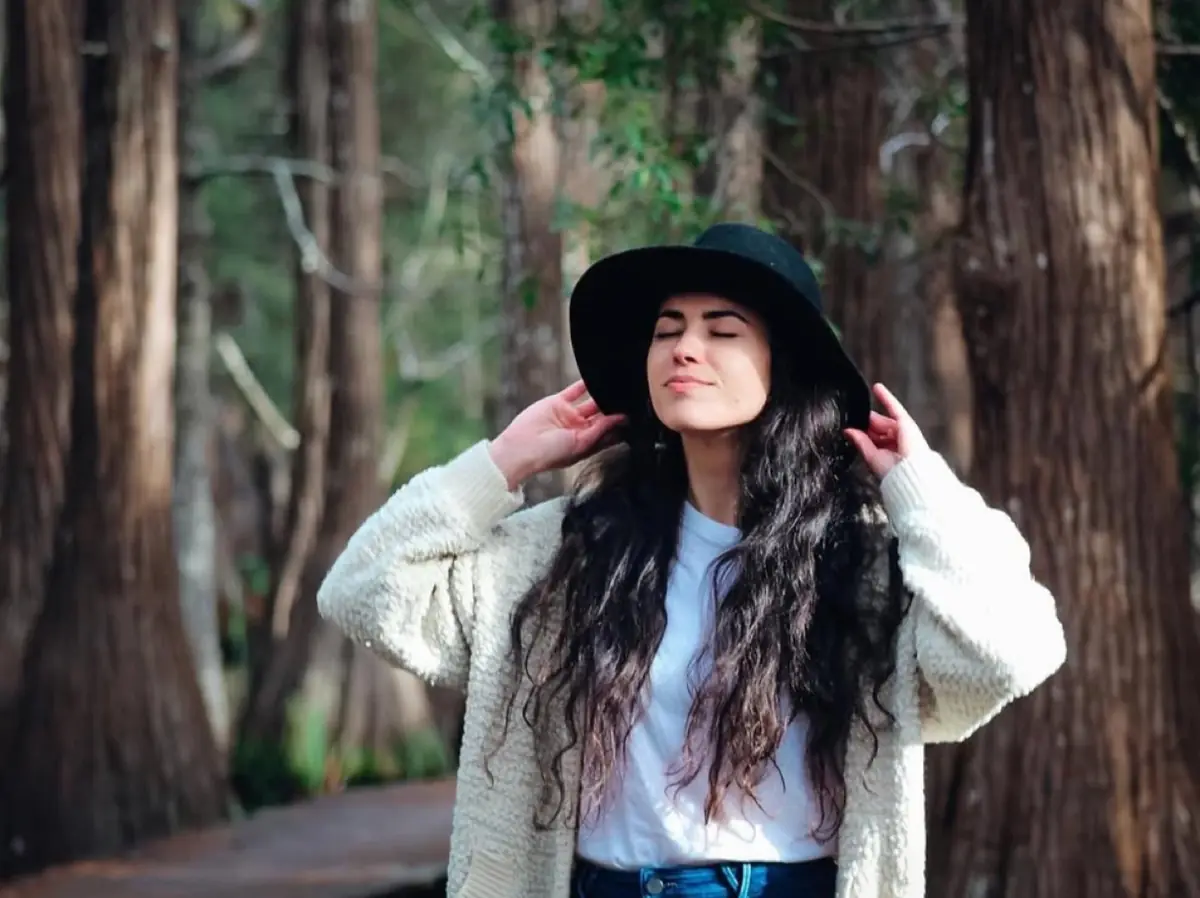 Ariel in a sun hat among tall trees